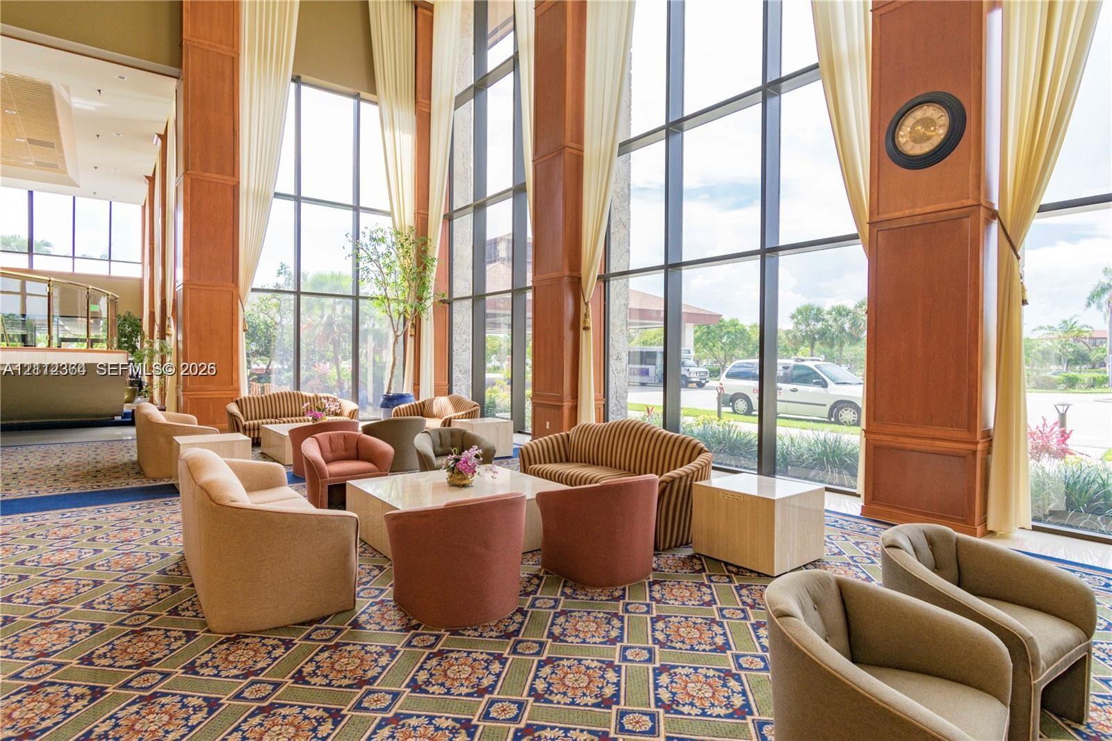 Floor-to-ceiling windows, wood-paneled pillars, and patterned wall-to-wall carpeting