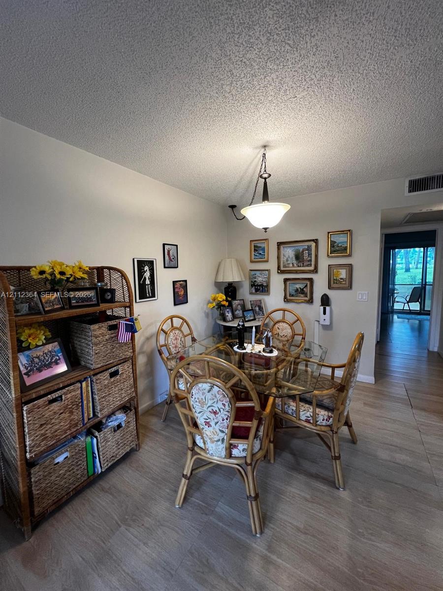 Wood-finish flooring and a central, neutral-toned hanging pendant light fixture