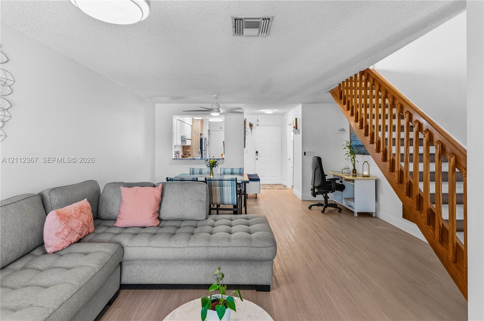 Wood-finish flooring, staircase with wood railings and balusters, and kitchen pass-through window