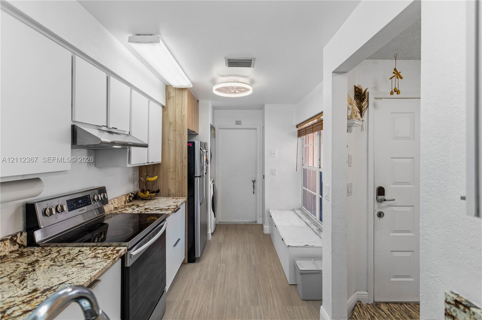 Kitchen featuring white cabinetry, stone-surface countertops, stainless steel electric range, wood-finish flooring, and built-in window seating