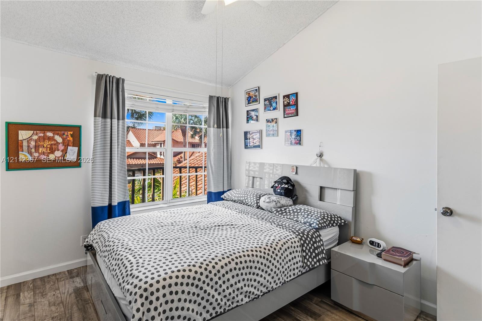 Vaulted ceiling, wood-finish flooring, multi-pane window, and white interior walls