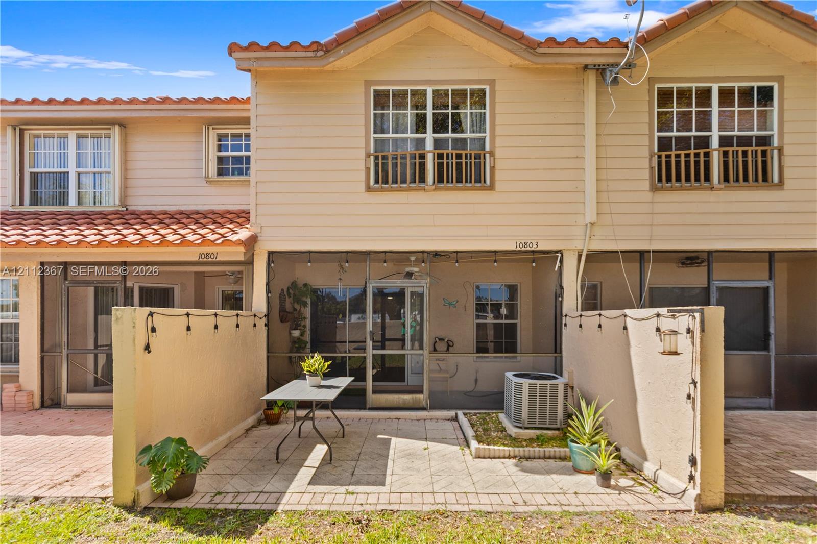 Two-story residence featuring a tile roof, lap siding, screened-in patio, and paver-stone exterior flooring
