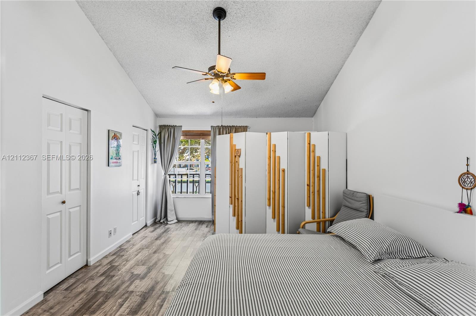 Vaulted ceilings, wood-finish flooring, two-panel interior doors, and a ceiling-mounted light fixture