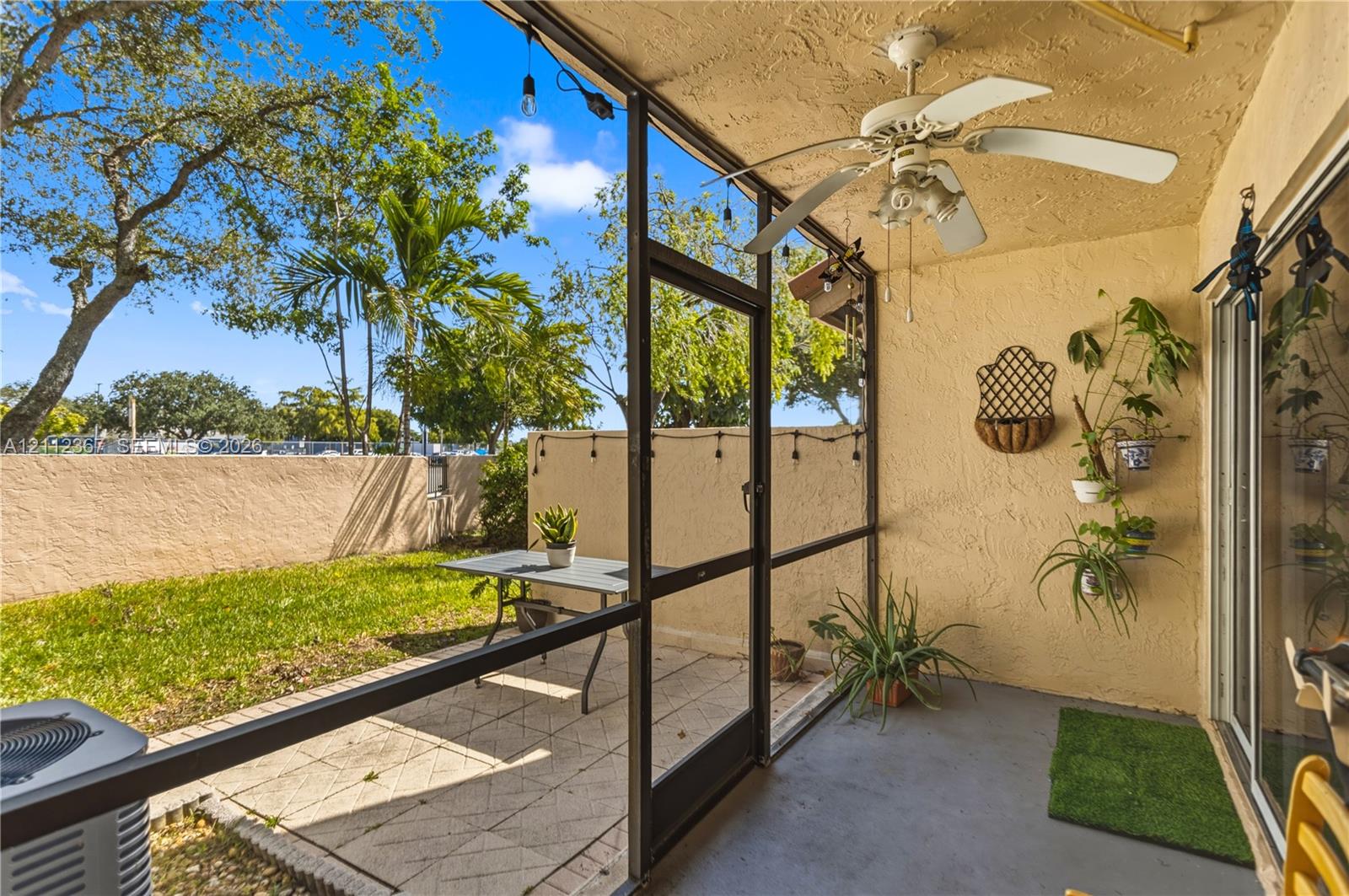 Screened-in patio featuring a concrete floor, ceiling fan, and masonry wall enclosure