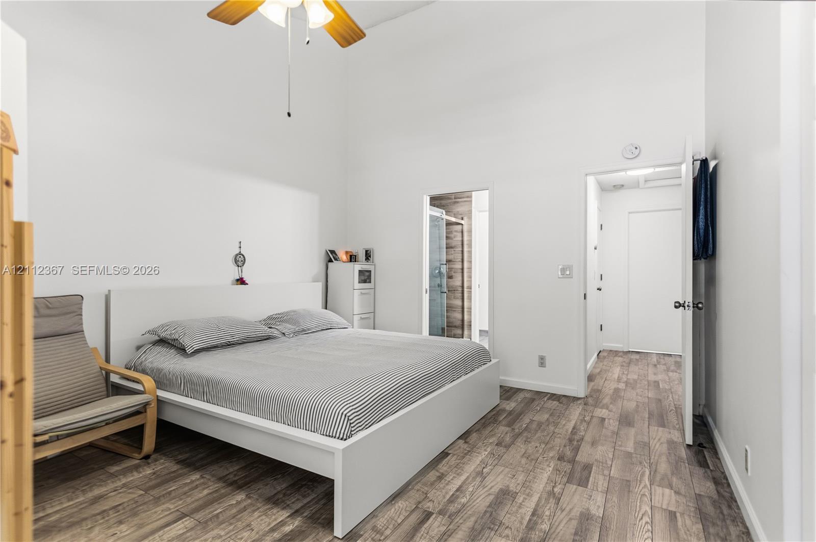 Room featuring high ceilings, wood-finish flooring, and a ceiling-mounted light fixture