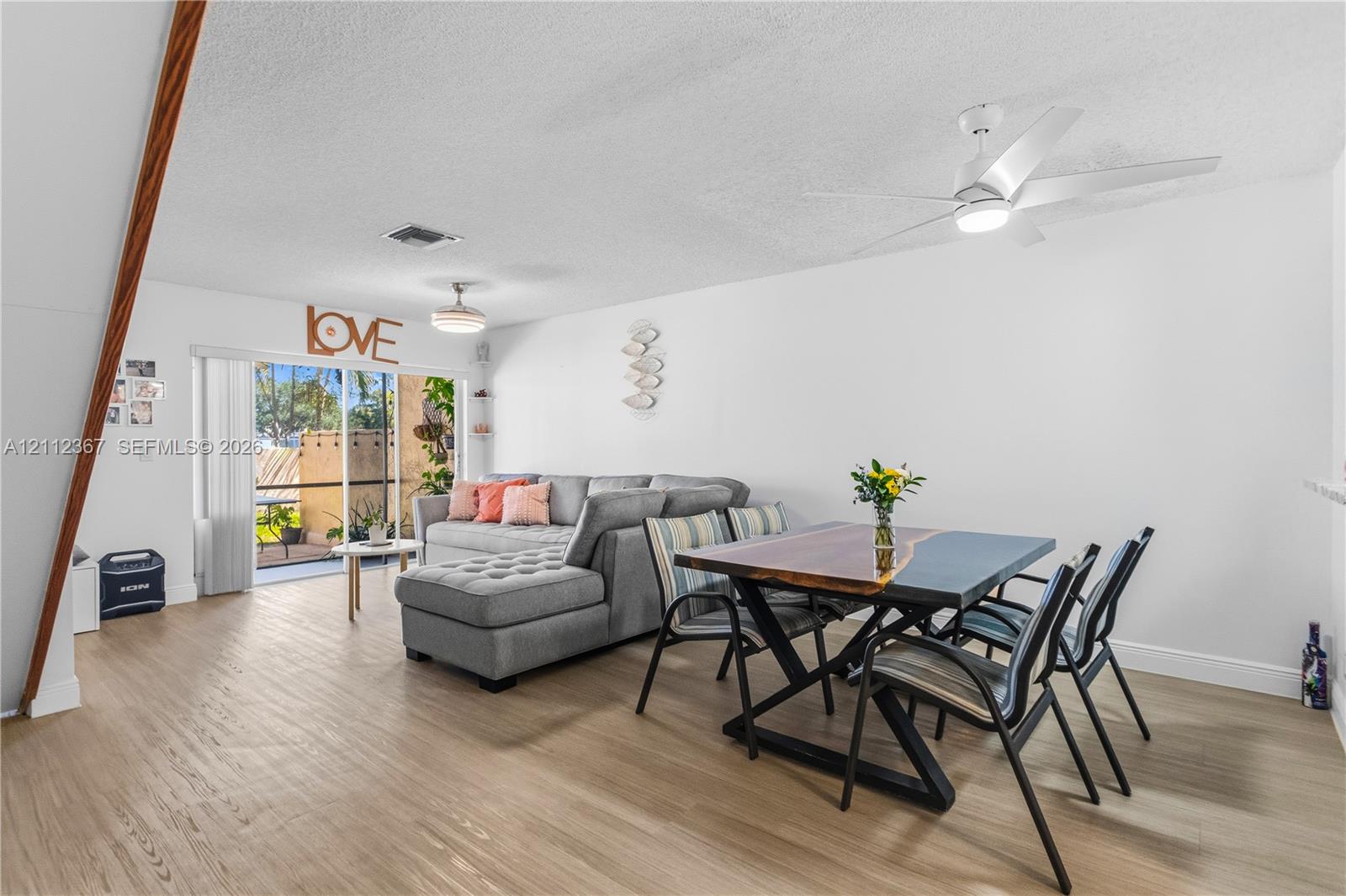 Wood-finish flooring, ceiling-mounted fan with integrated lighting, and sliding glass doors