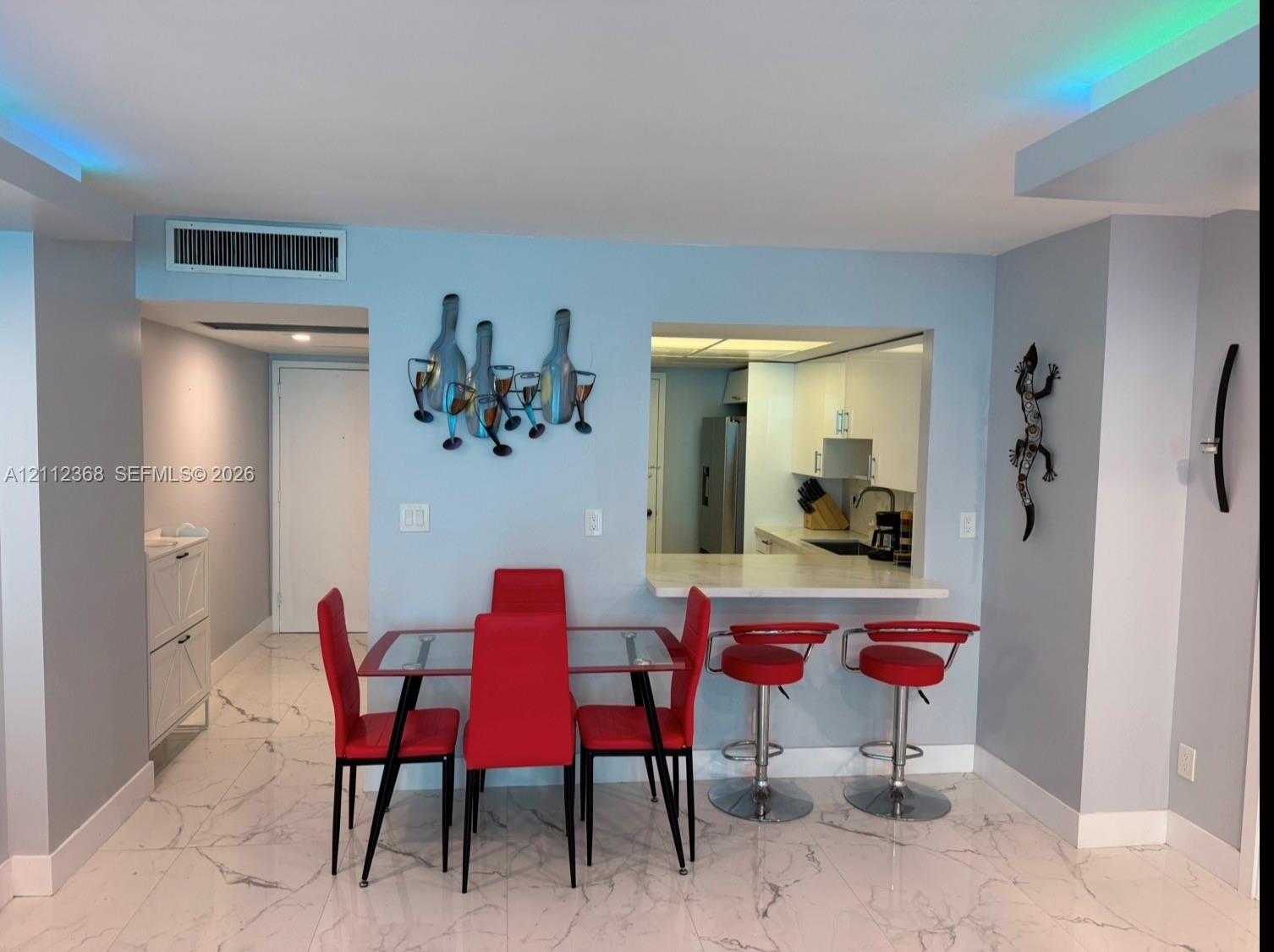 Polished stone flooring with veining, breakfast bar featuring stone countertop, recessed ceiling lighting, and crisp white cabinetry