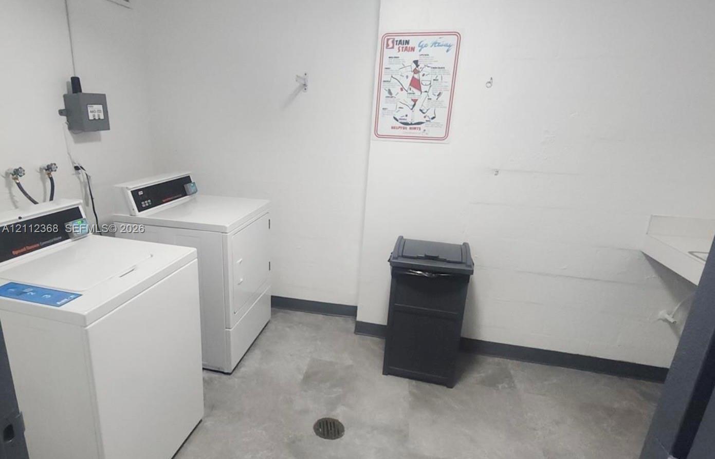 Utility room featuring large-format tile flooring, dedicated washer and dryer hookups, and a built-in wall-mounted sink basin