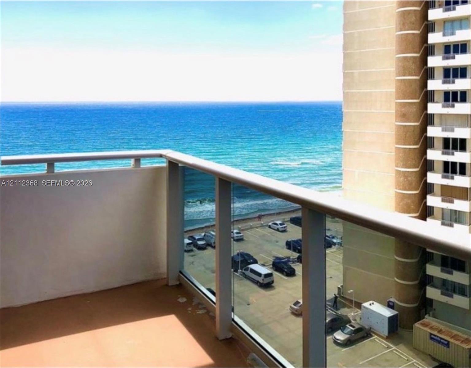 Private balcony featuring glass-panel railings and oceanfront exposure