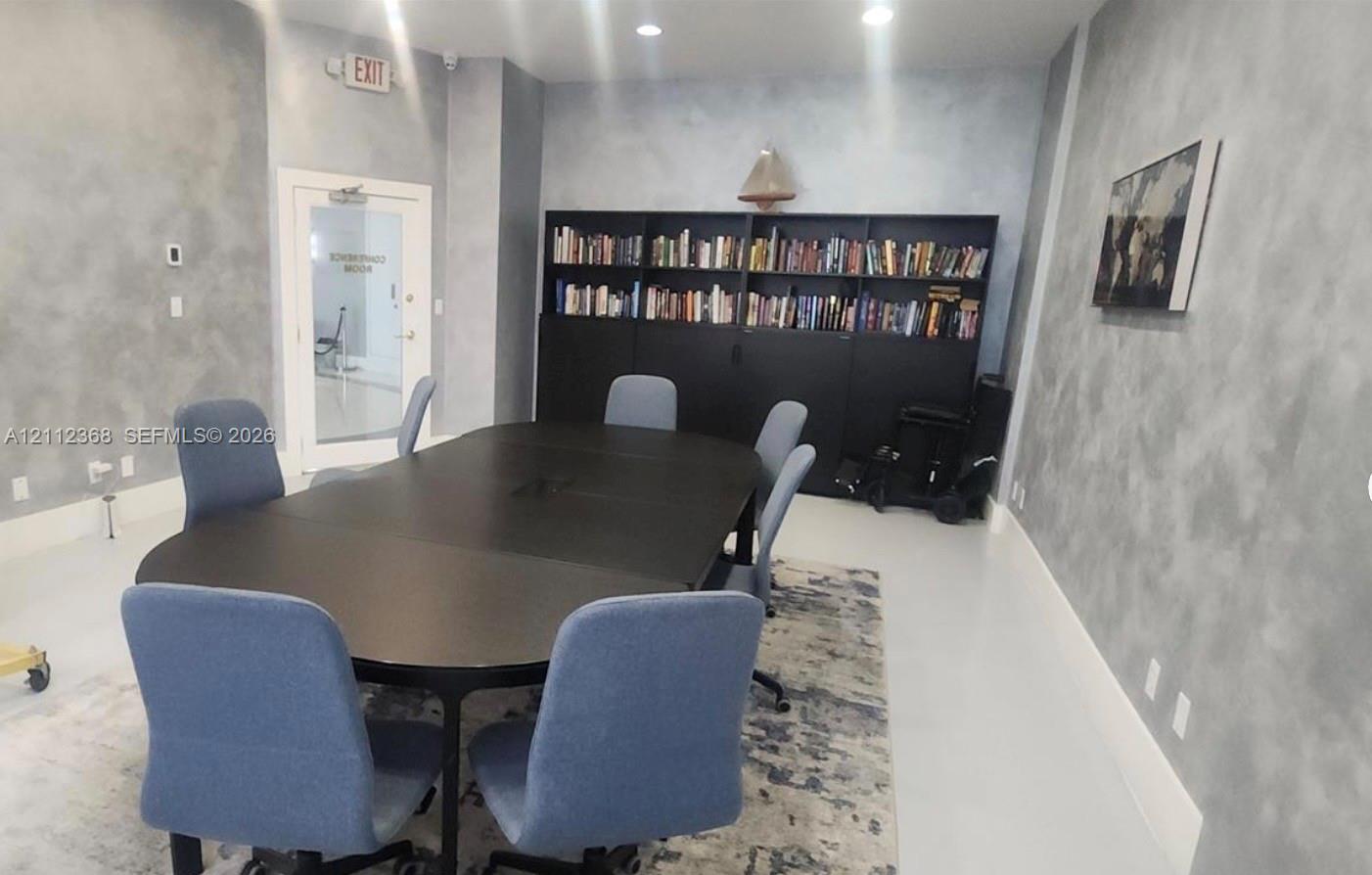Room featuring textured grey wall finishes, recessed lighting, and a floor-to-ceiling built-in dark finish shelving unit