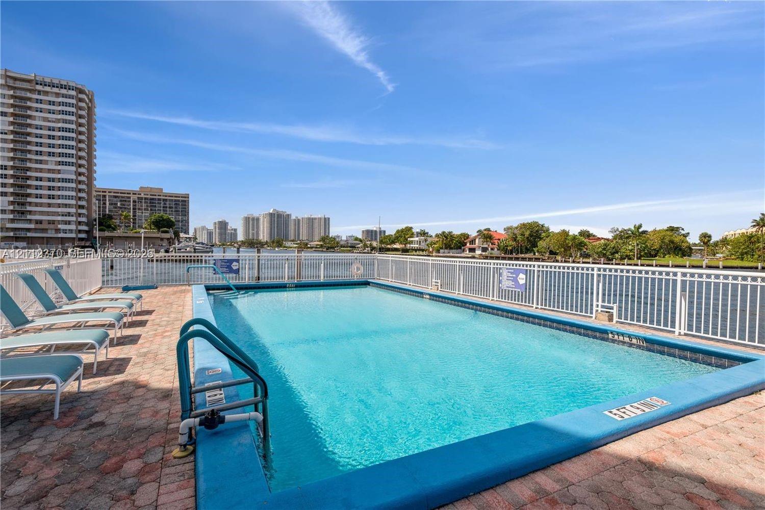 Rectangular swimming pool featuring a brick-paver deck and white metal fencing Rectangular swimming pool featuring a brick-paver deck and white metal fencing