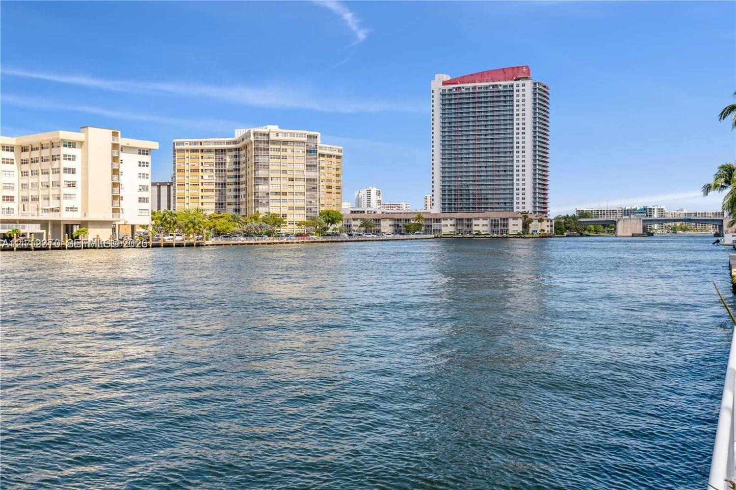 Waterfront perspective featuring a waterway with multi-story residential architecture and bridge infrastructure Waterfront perspective featuring a waterway with multi-story residential architecture and bridge infrastructure