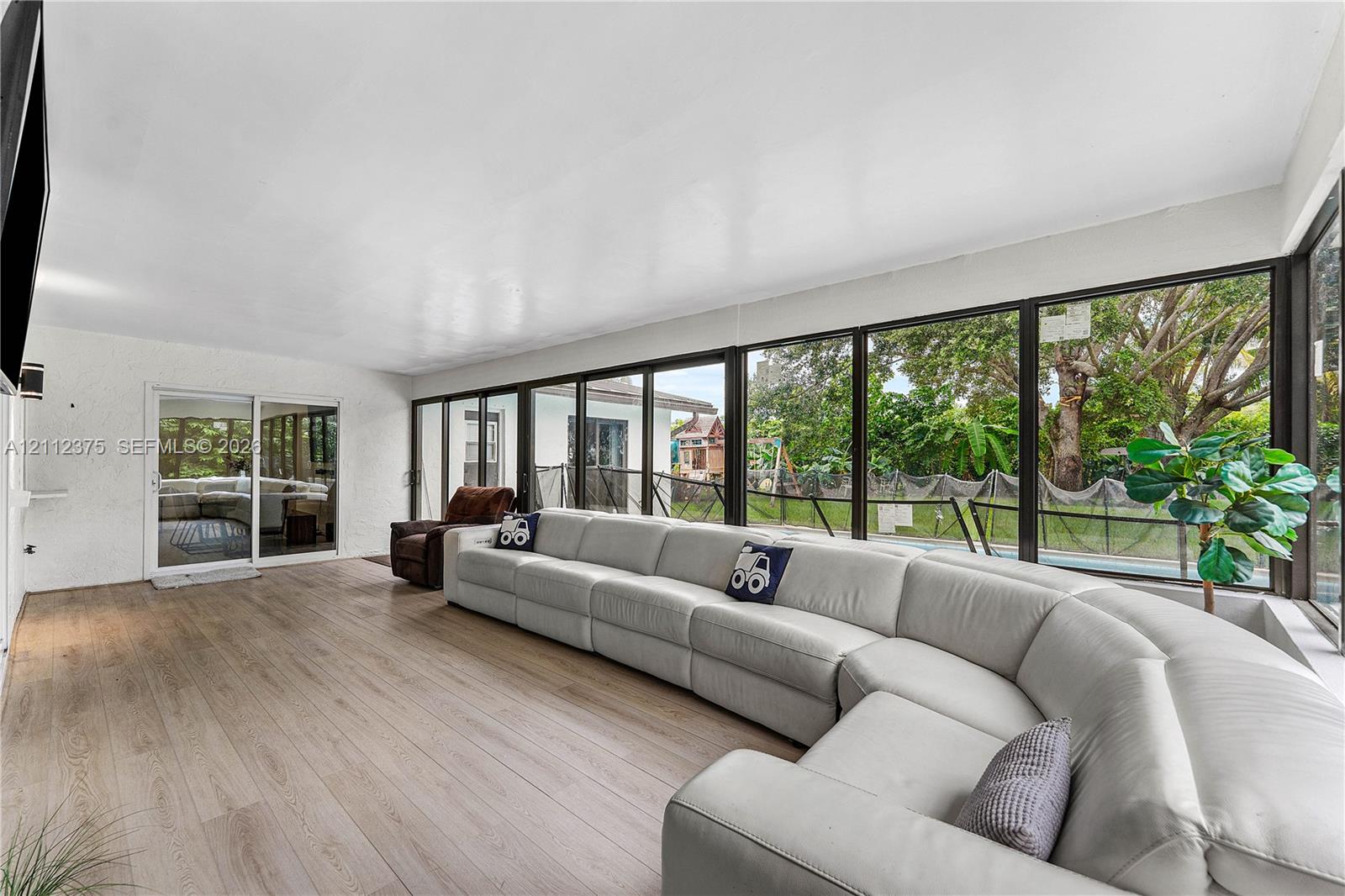 Expansive sunroom featuring full-height walls of glass, wood-finish flooring, and sliding glass door access to the exterior