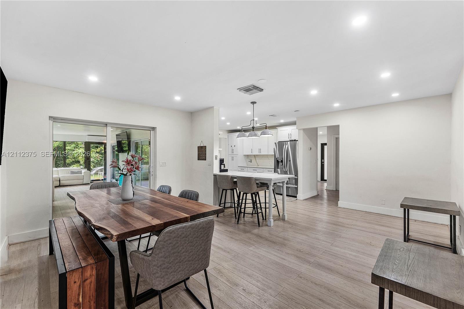 Open concept space featuring recessed lighting, wood-finish flooring, a kitchen island with built-in cabinetry, and sliding glass doors