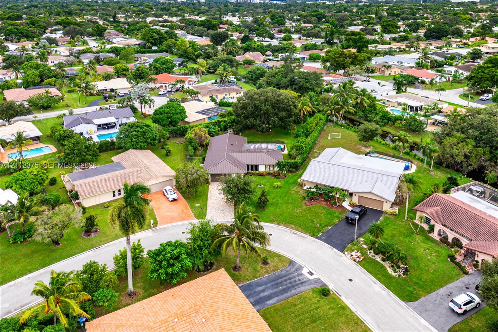 Aerial perspective of a suburban neighborhood featuring mature landscaping, winding roads, and expansive green spaces