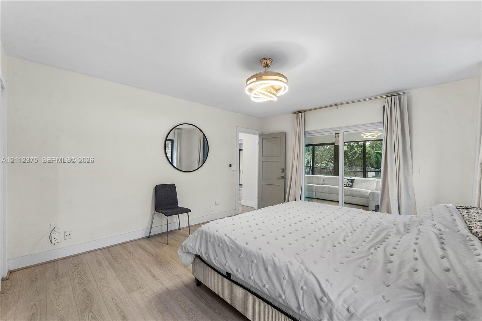 Wood-finish flooring, contemporary geometric flush-mount light fixture, and floor-to-ceiling sliding glass doors