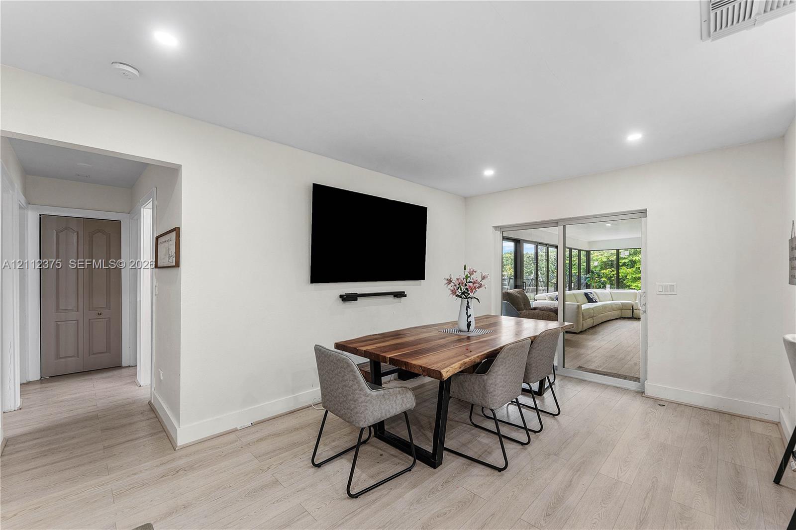 Neutral-toned interior featuring wood-finish flooring, recessed lighting, and a sliding glass door