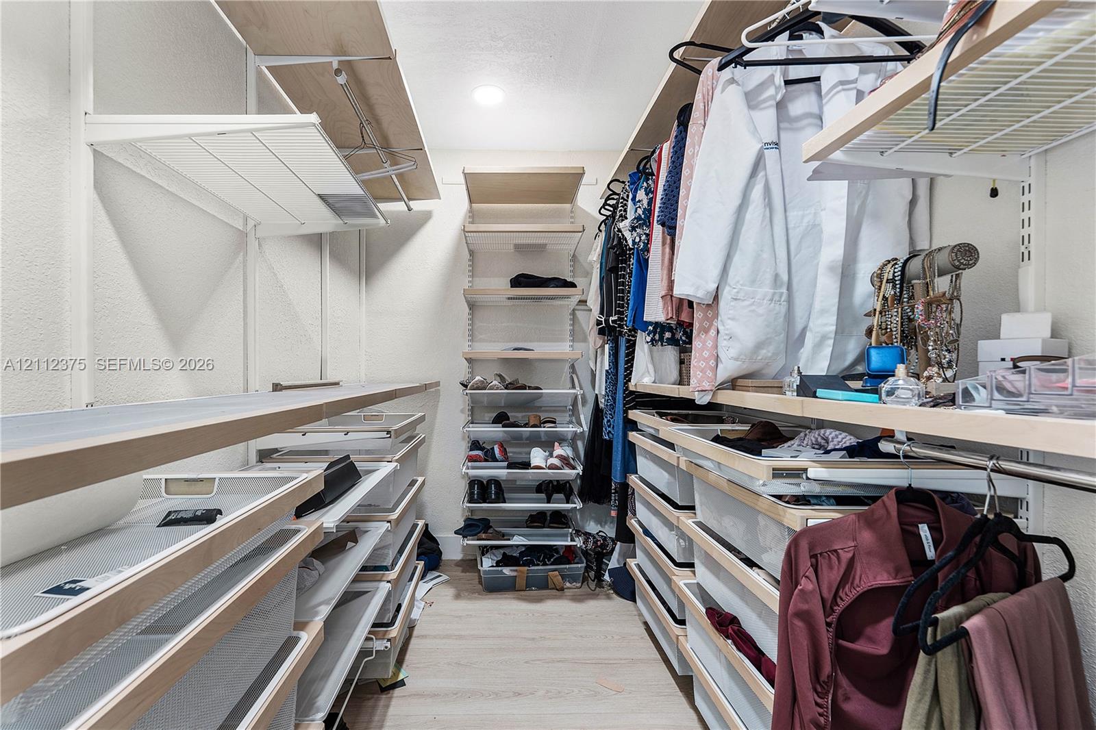 Custom walk-in closet featuring built-in shelving, integrated pull-out drawers, overhead storage racks, and recessed lighting