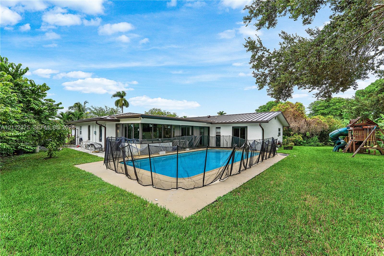 Private backyard featuring an in-ground swimming pool, concrete pool deck, and expansive lawn area