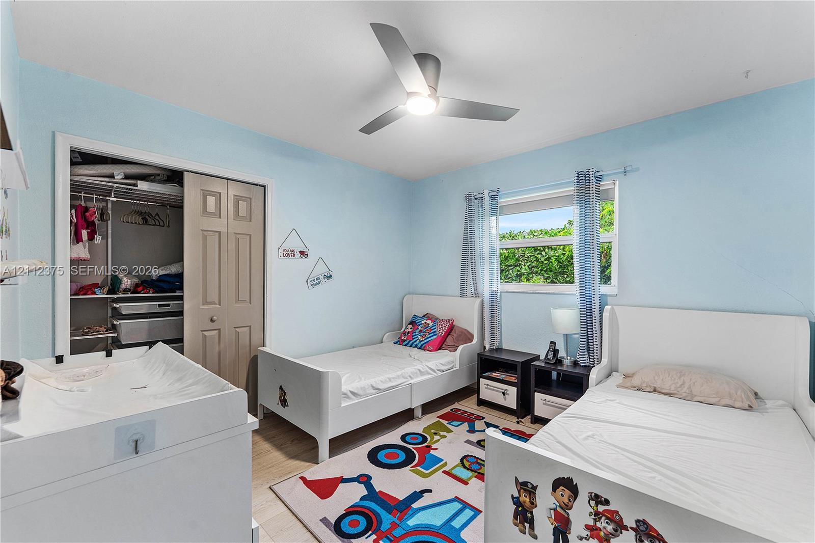 Bedroom featuring wood-finish flooring, a contemporary three-blade ceiling fan with integrated lighting, and a closet with bifold doors