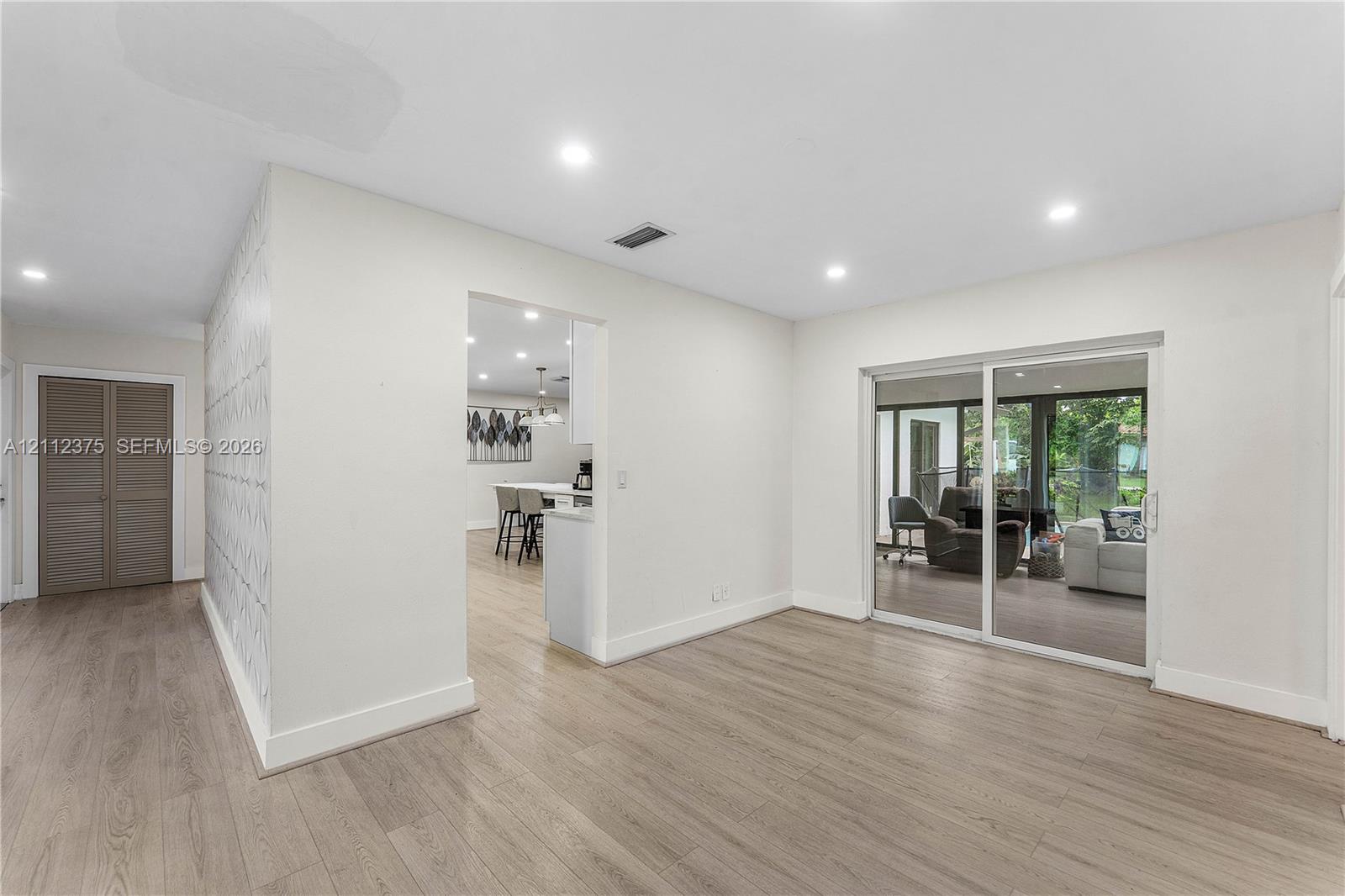 Interior featuring wood-finish flooring, recessed lighting, sliding glass doors, and patterned accent wall
