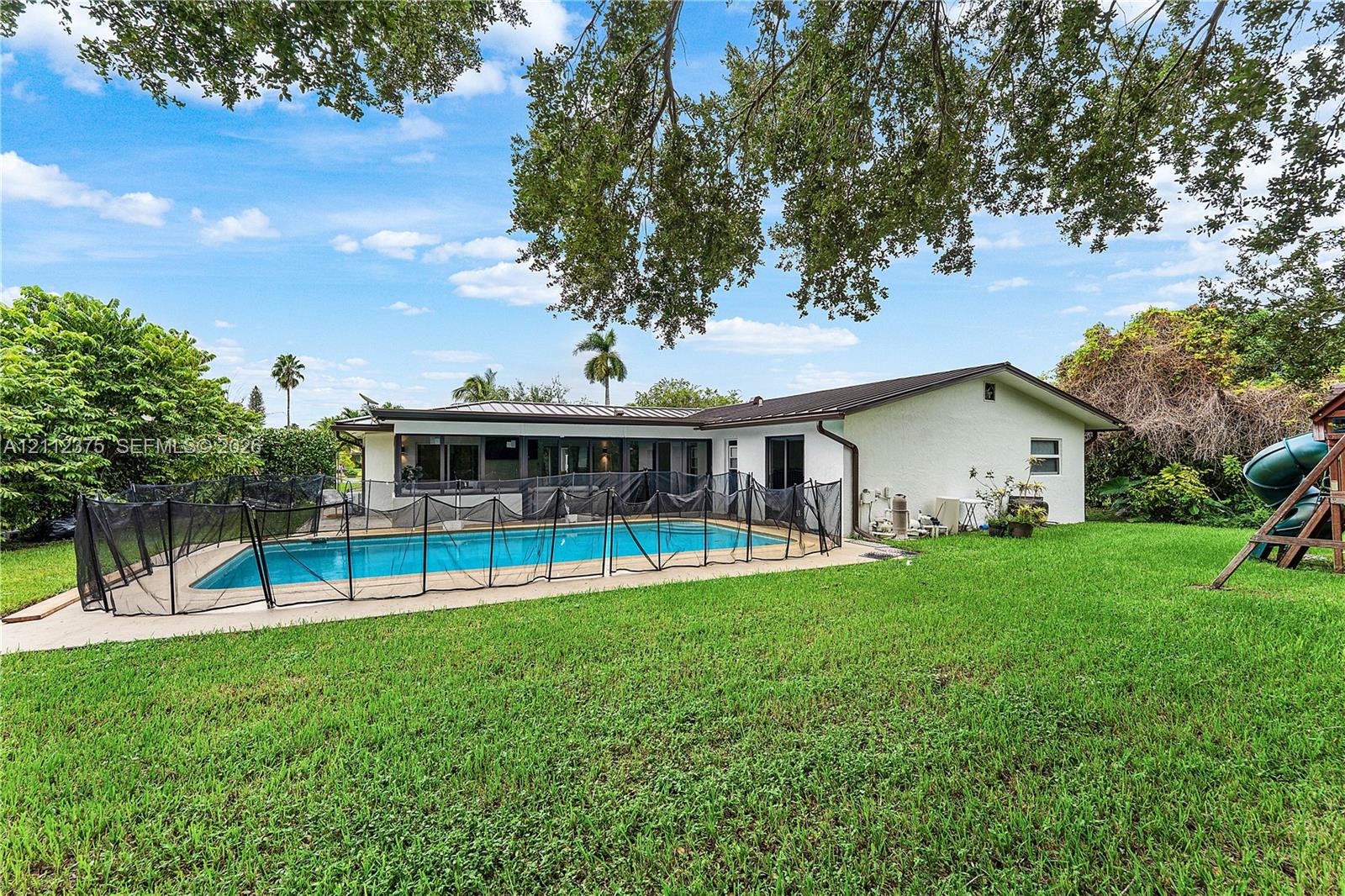 Exterior featuring a swimming pool with a surrounding concrete deck and mature shade trees