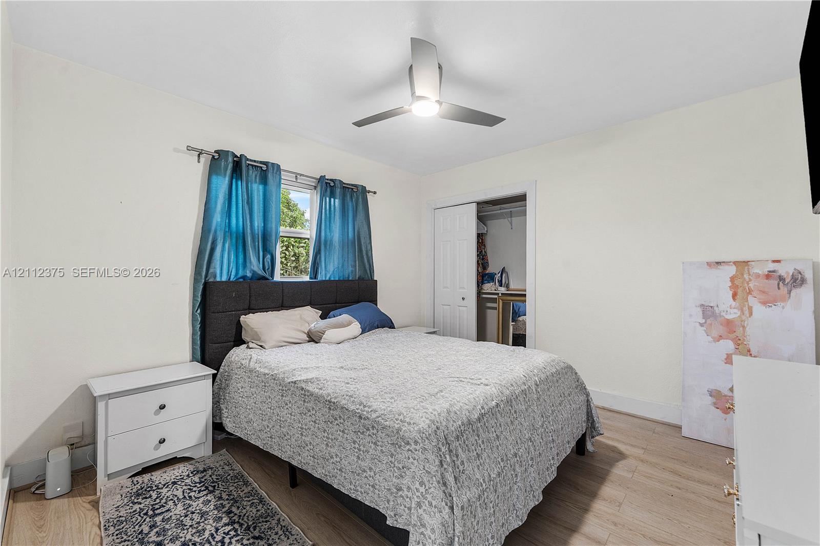 Light-filled room featuring wood-finish flooring, a ceiling fan with integrated lighting, and a closet with paneled doors