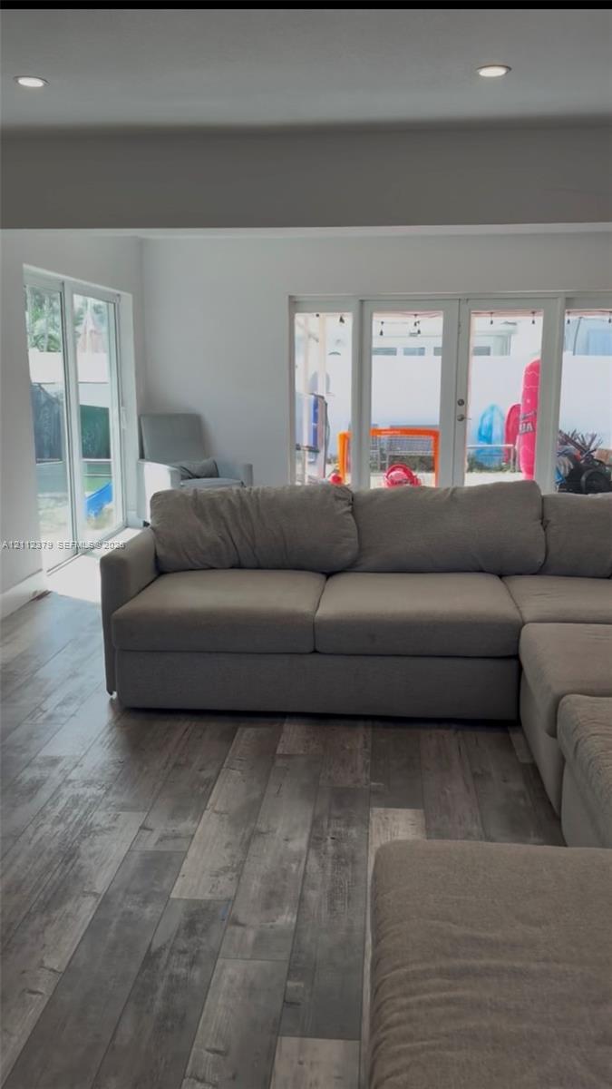 Wood-finish flooring, recessed lighting, and multiple sets of glass-paned doors providing exterior access