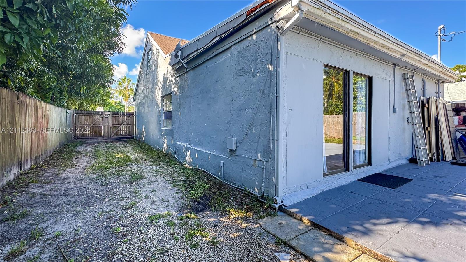 Stucco exterior featuring a concrete patio, sliding glass door, and wooden privacy fencing