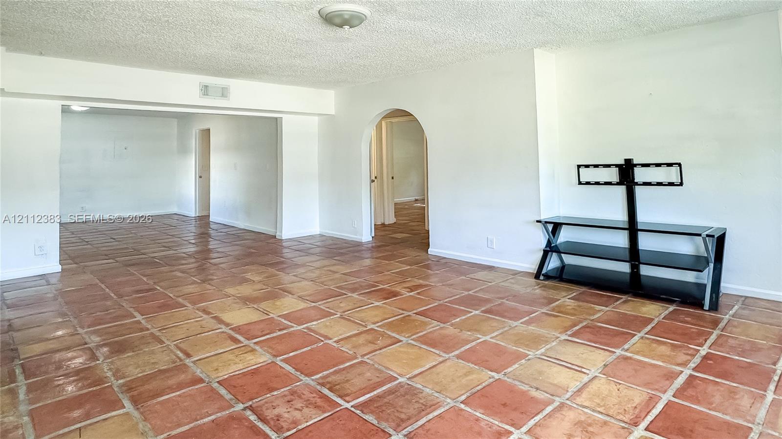 Interior space featuring terra cotta tile flooring and an arched entryway
