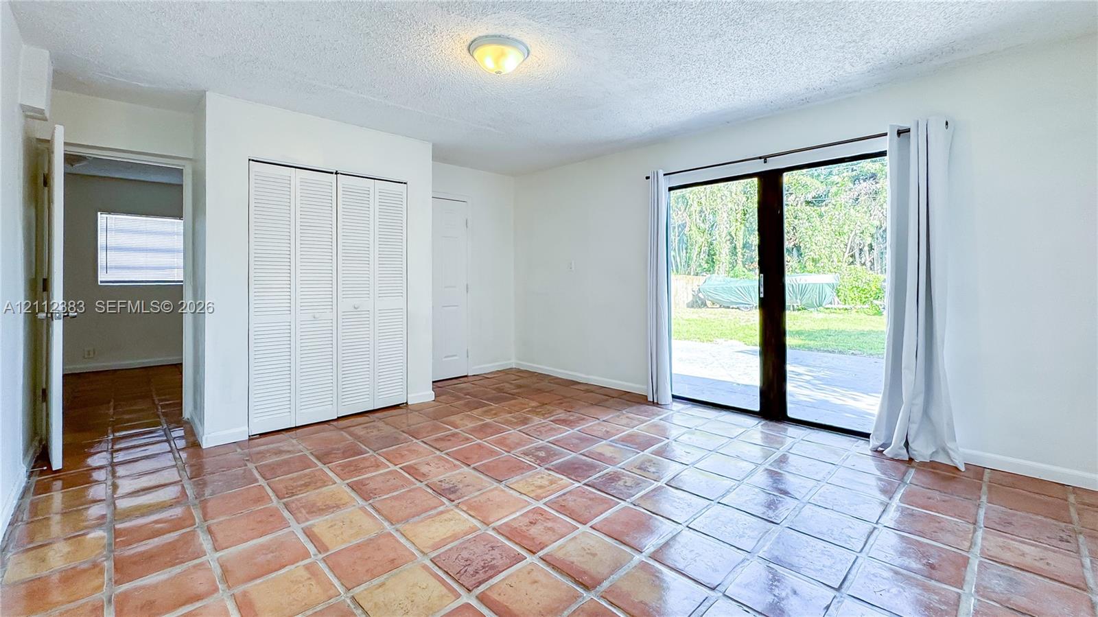 Ceramic tile flooring, sliding glass door, white bifold closet doors, and flush-mount ceiling lighting