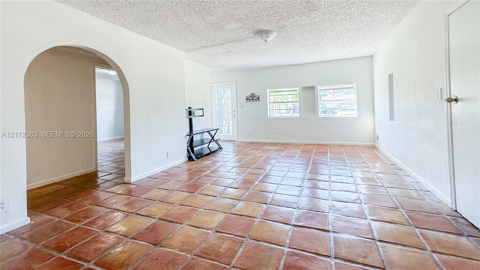 Interior space featuring natural stone-finish tile flooring, an arched entryway, and a full-light glass panel exterior door