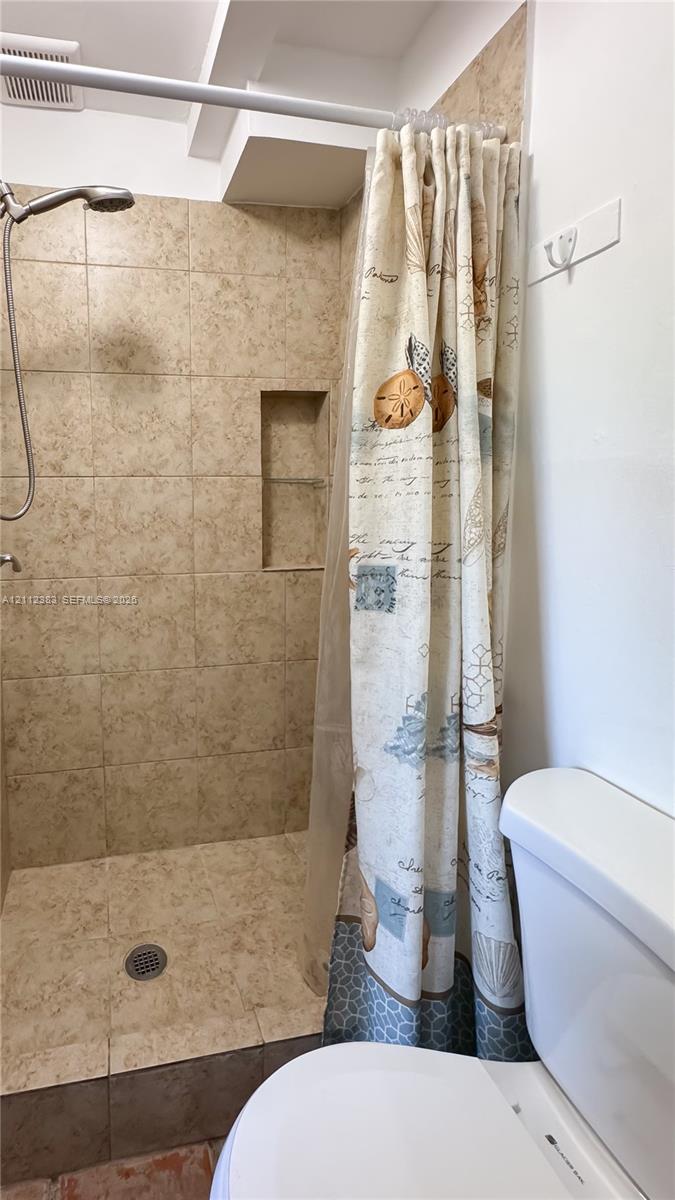 Walk-in shower featuring floor-to-ceiling tile, a built-in recessed storage niche, and a wall-mounted shower head
