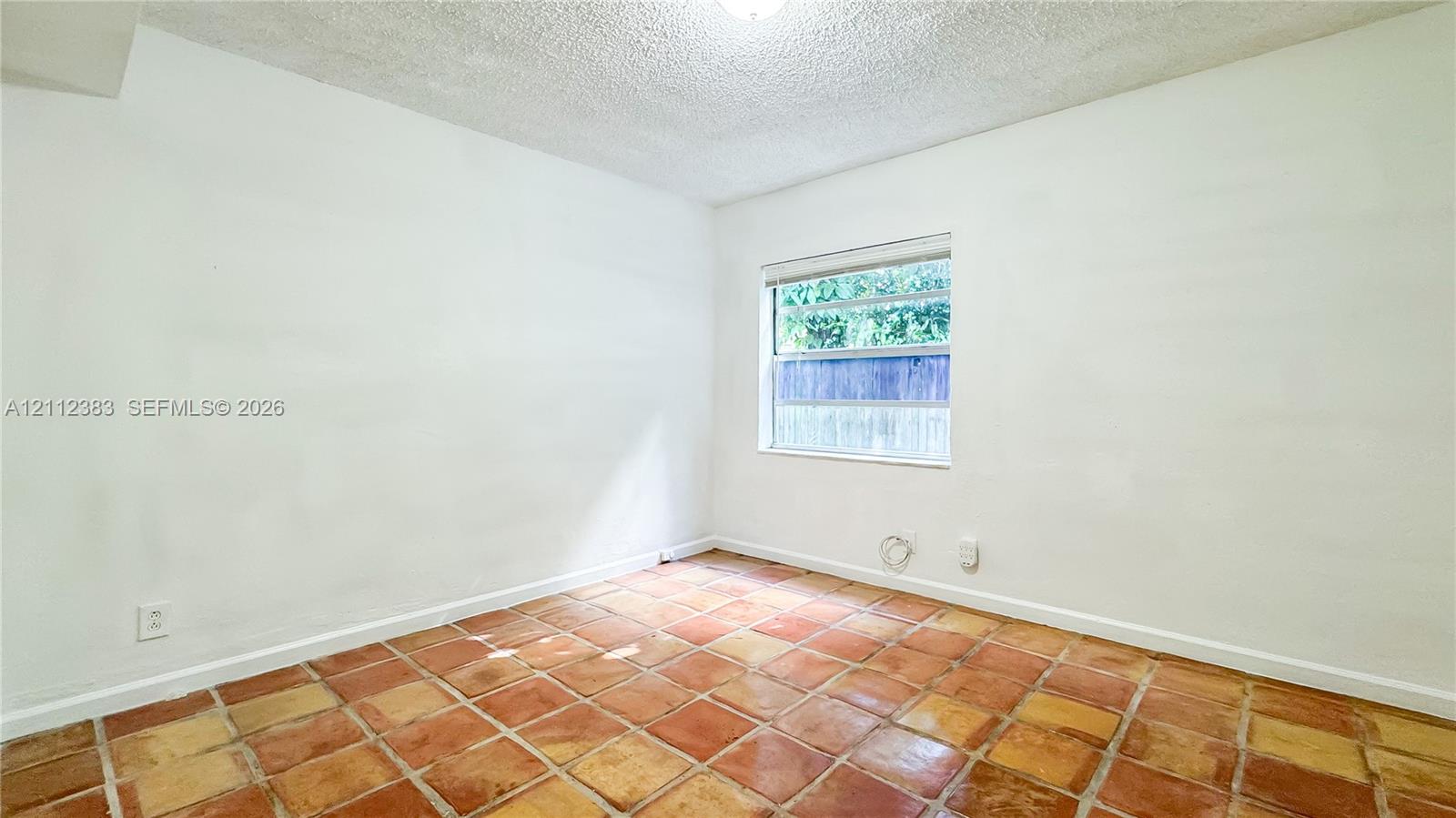 Interior room featuring textured ceiling, neutral walls, and terracotta-style tile flooring