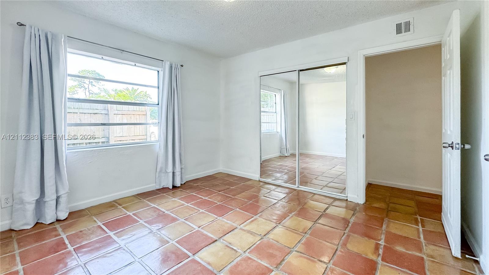 Interior room featuring tile flooring, sliding mirrored closet doors, and multi-pane window