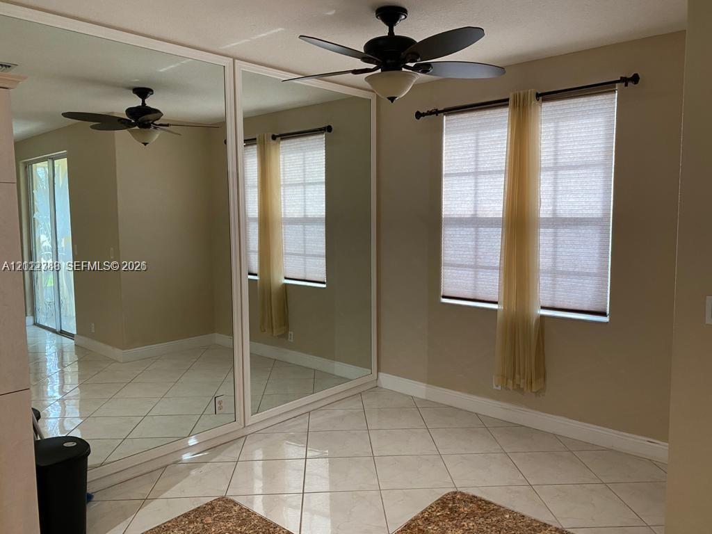 Large wall-mounted mirror panels, diagonal tile flooring, ceiling fan with integrated lighting, and multi-pane windows with hardware