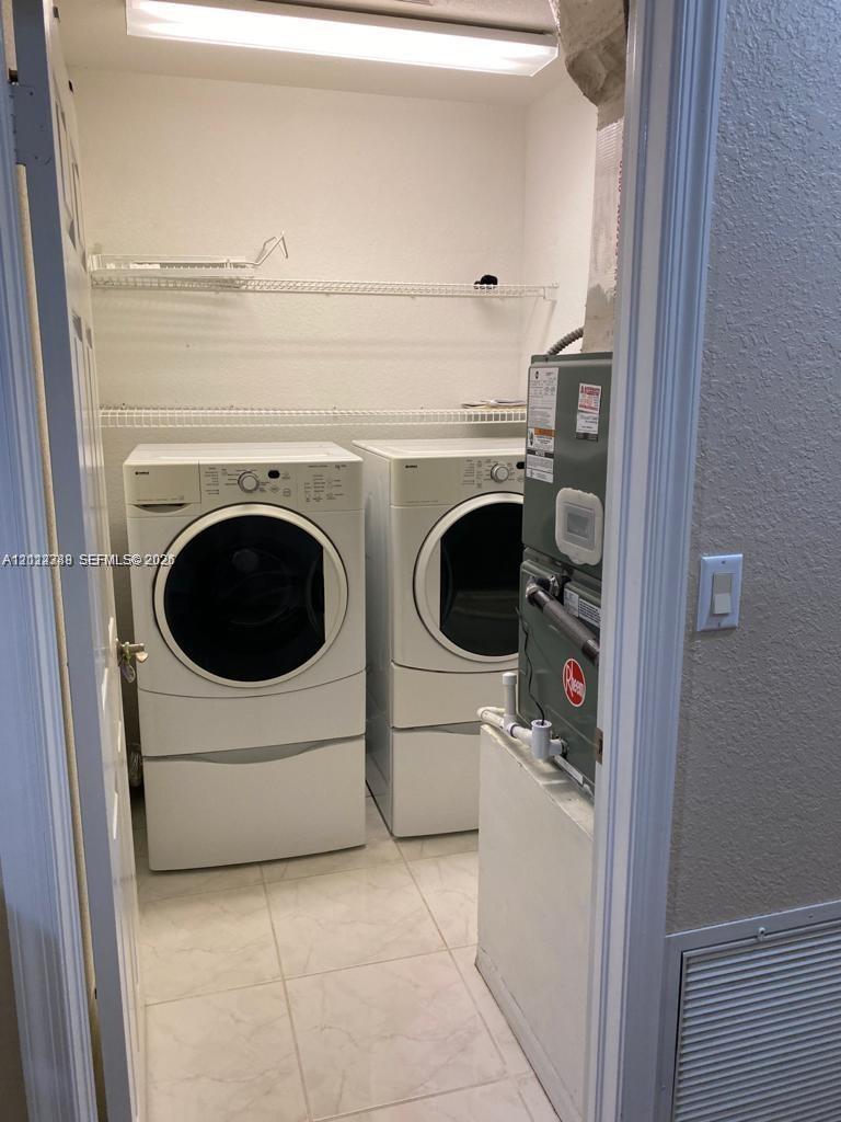 Utility closet featuring tiled flooring, overhead recessed lighting, and wall-mounted wire shelving