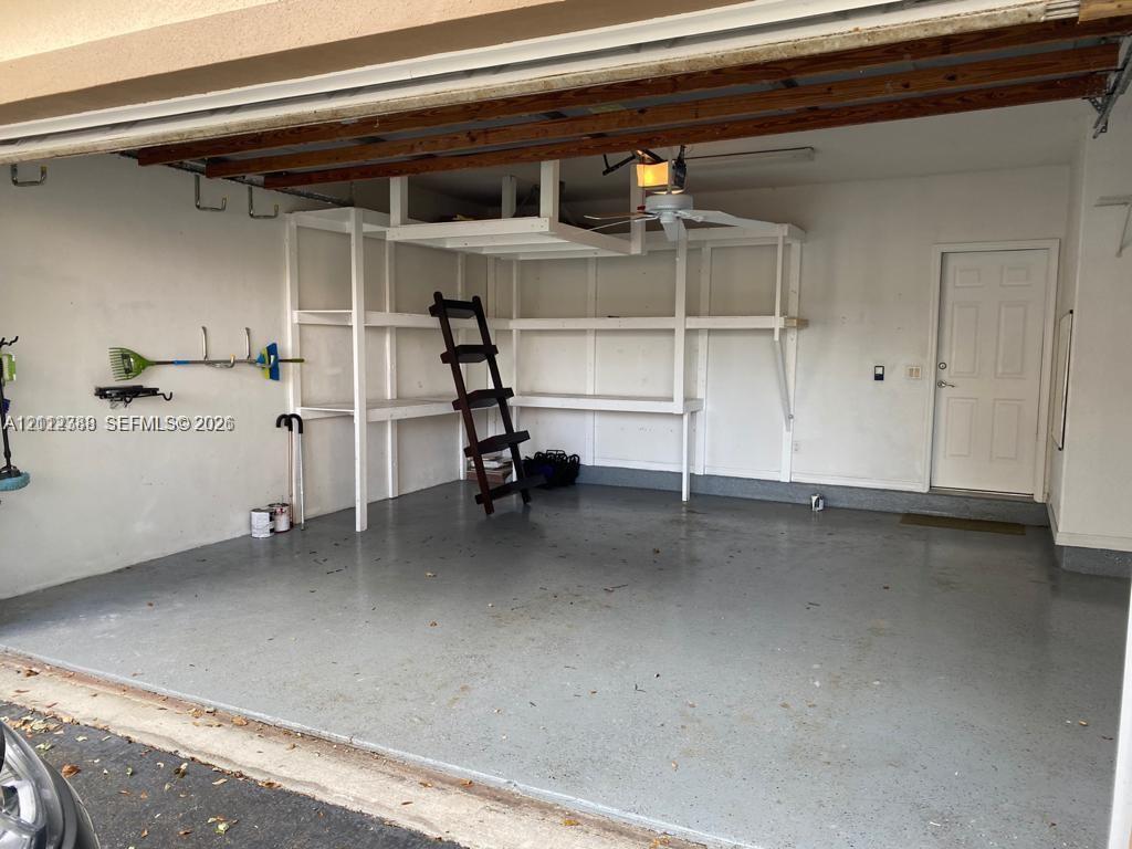 Garage featuring an epoxy-coated floor, integrated built-in shelving, overhead storage, and an exterior access door