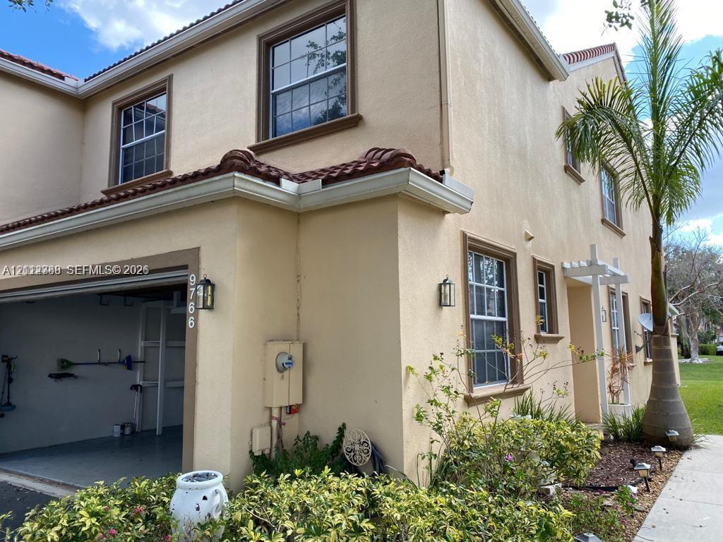 Stucco exterior featuring a clay tile roof, multi-pane windows, and an integrated garage Stucco exterior featuring a clay tile roof, multi-pane windows, and an integrated garage