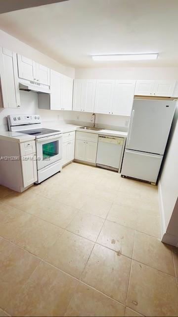 Kitchen featuring white cabinetry, solid-surface countertops, tile flooring, and integrated white appliances Kitchen featuring white cabinetry, solid-surface countertops, tile flooring, and integrated white appliances