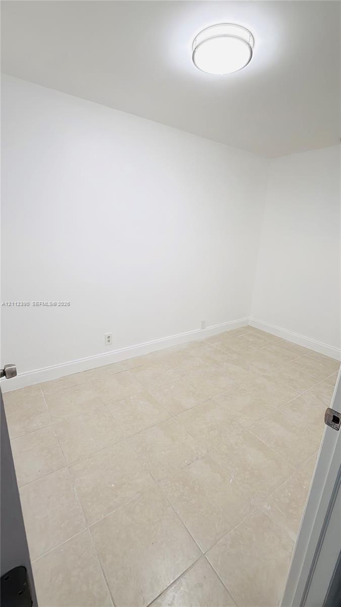 Neutral-toned tile flooring, white wall finishes, and a flush-mount dome ceiling light fixture Neutral-toned tile flooring, white wall finishes, and a flush-mount dome ceiling light fixture