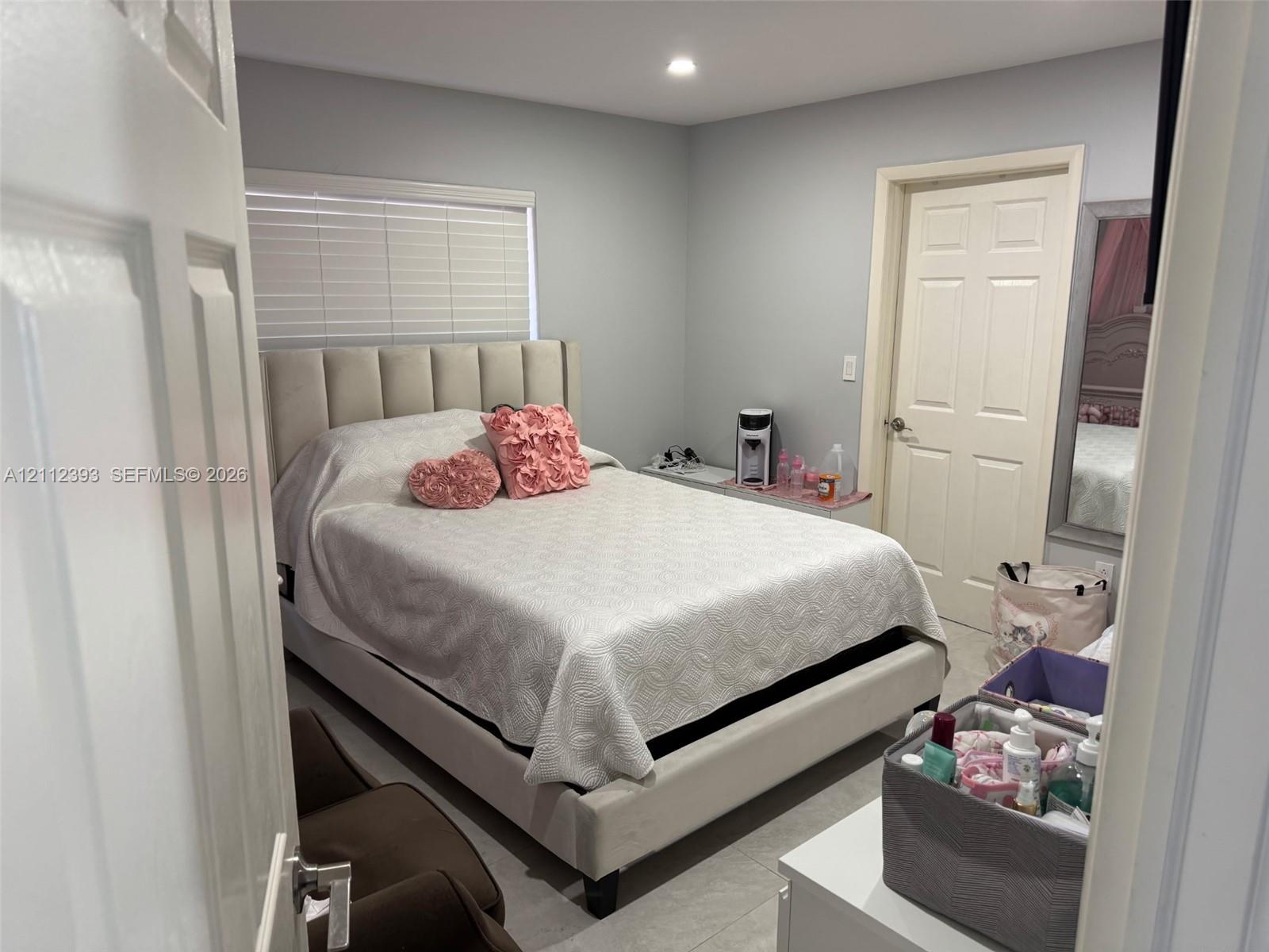 Neutral-toned interior featuring recessed lighting, a multi-panel interior door, and large-format tile flooring