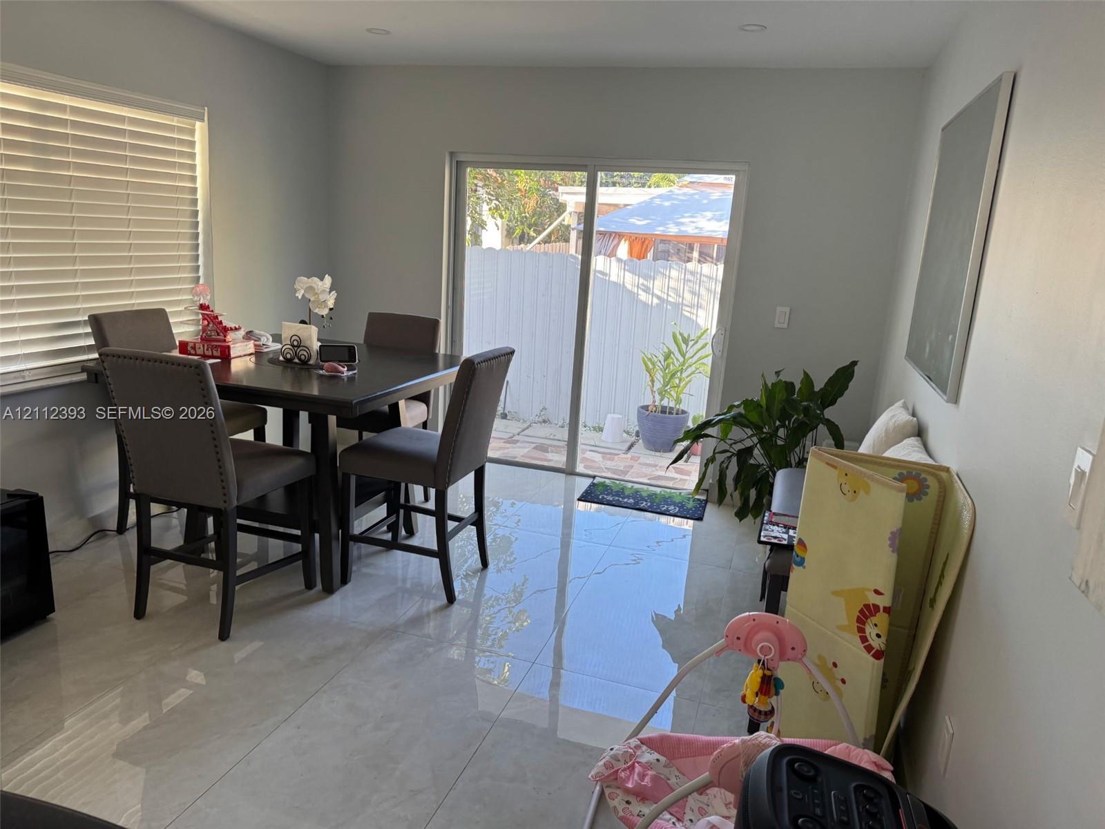 Large-format porcelain tile flooring, sliding glass door, recessed lighting, and horizontal window blinds