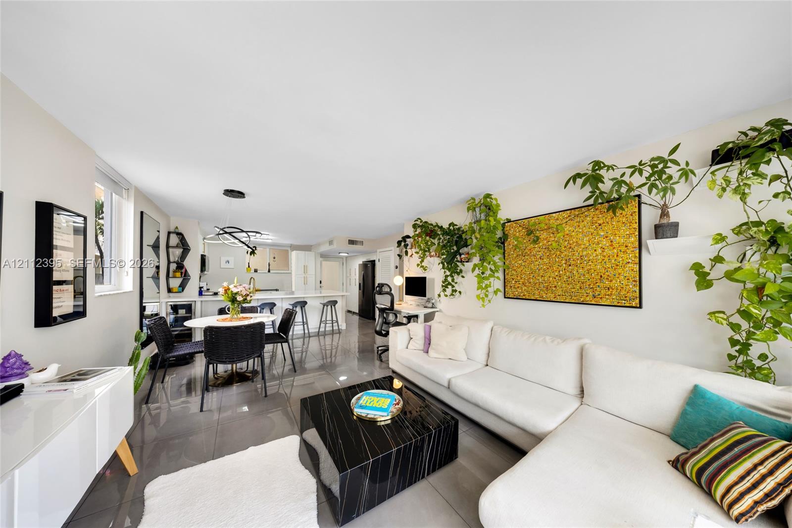 Open concept living space featuring polished tile flooring, recessed lighting, and a modern kitchen island with breakfast bar seating