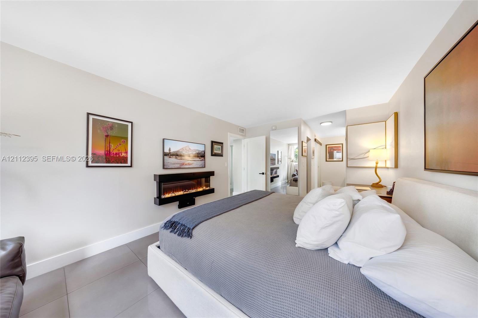 Wall-mounted electric fireplace, grey tile flooring, and neutral wall tones