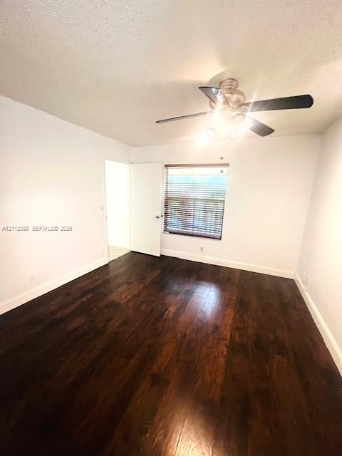 Interior room featuring dark wood-finish flooring, a ceiling fan with integrated lighting, and horizontal window blinds