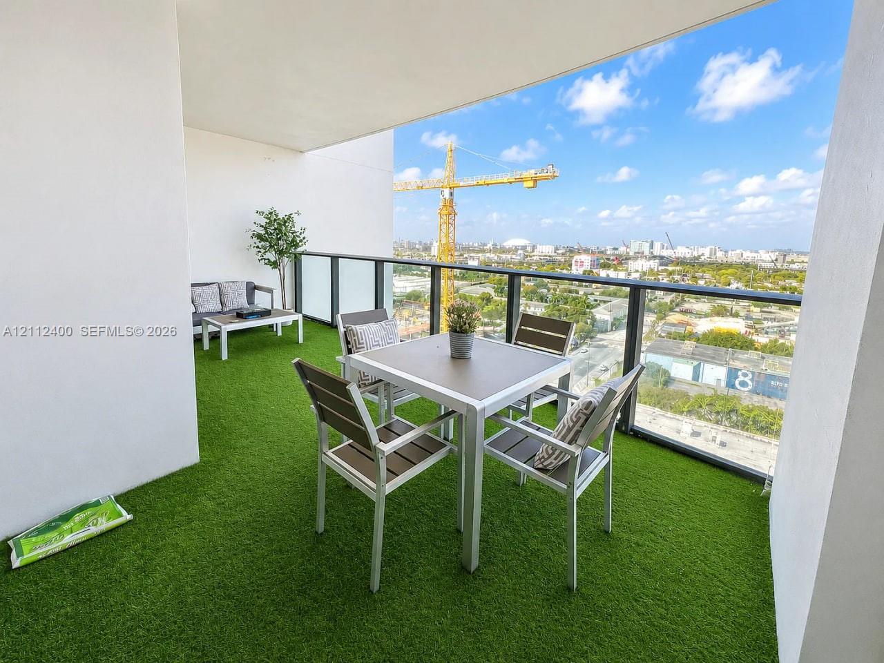 Covered balcony featuring synthetic turf flooring and a metal-framed glass railing Covered balcony featuring synthetic turf flooring and a metal-framed glass railing