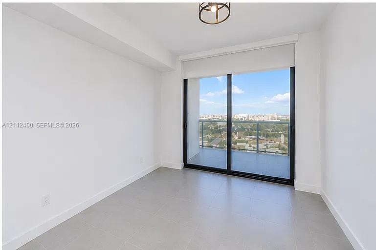 Neutral-toned tile flooring, floor-to-ceiling sliding glass doors, integrated balcony access, and a metal-railing exterior enclosure