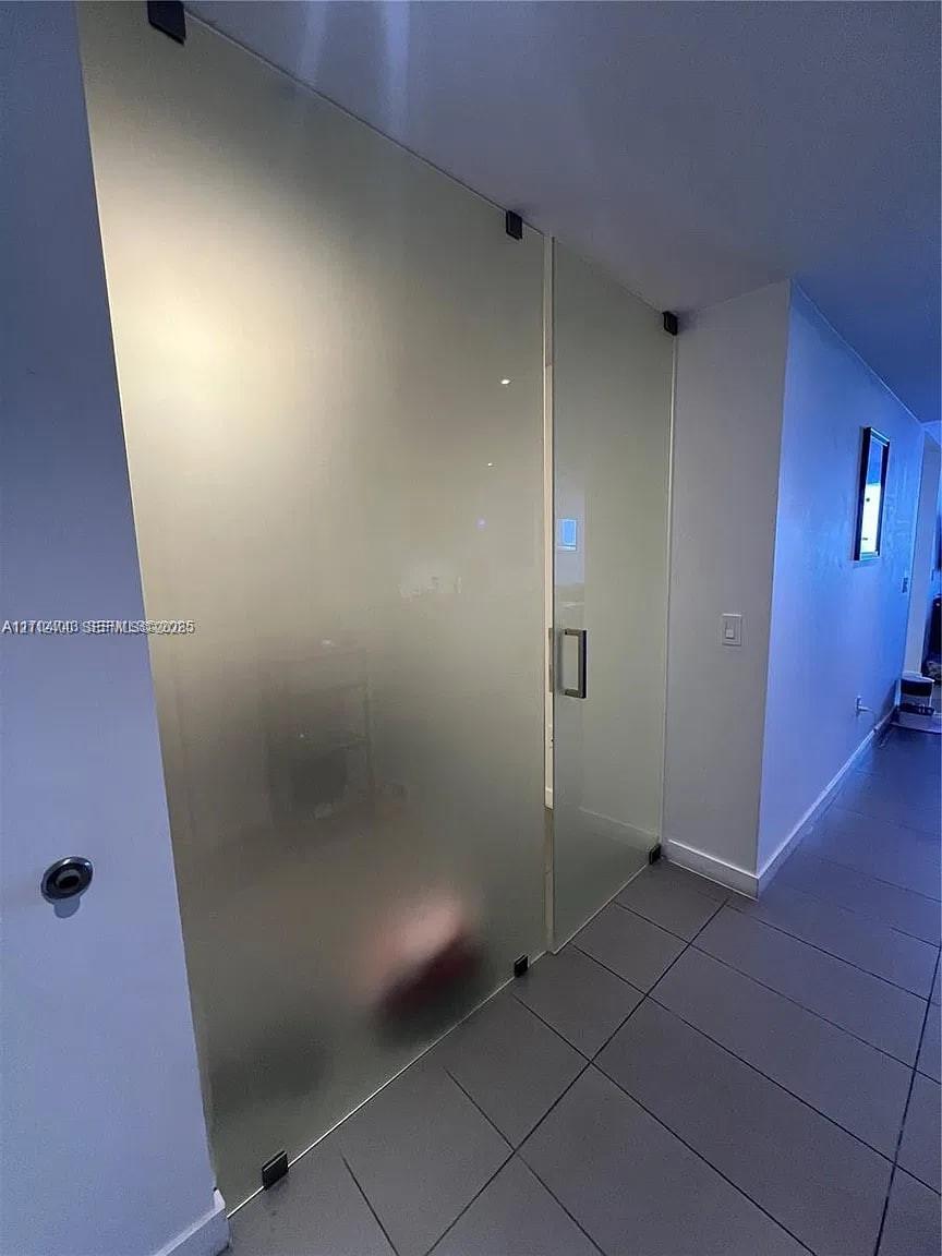 Frosted glass sliding doors with matte black hardware and large-format tile flooring Frosted glass sliding doors with matte black hardware and large-format tile flooring
