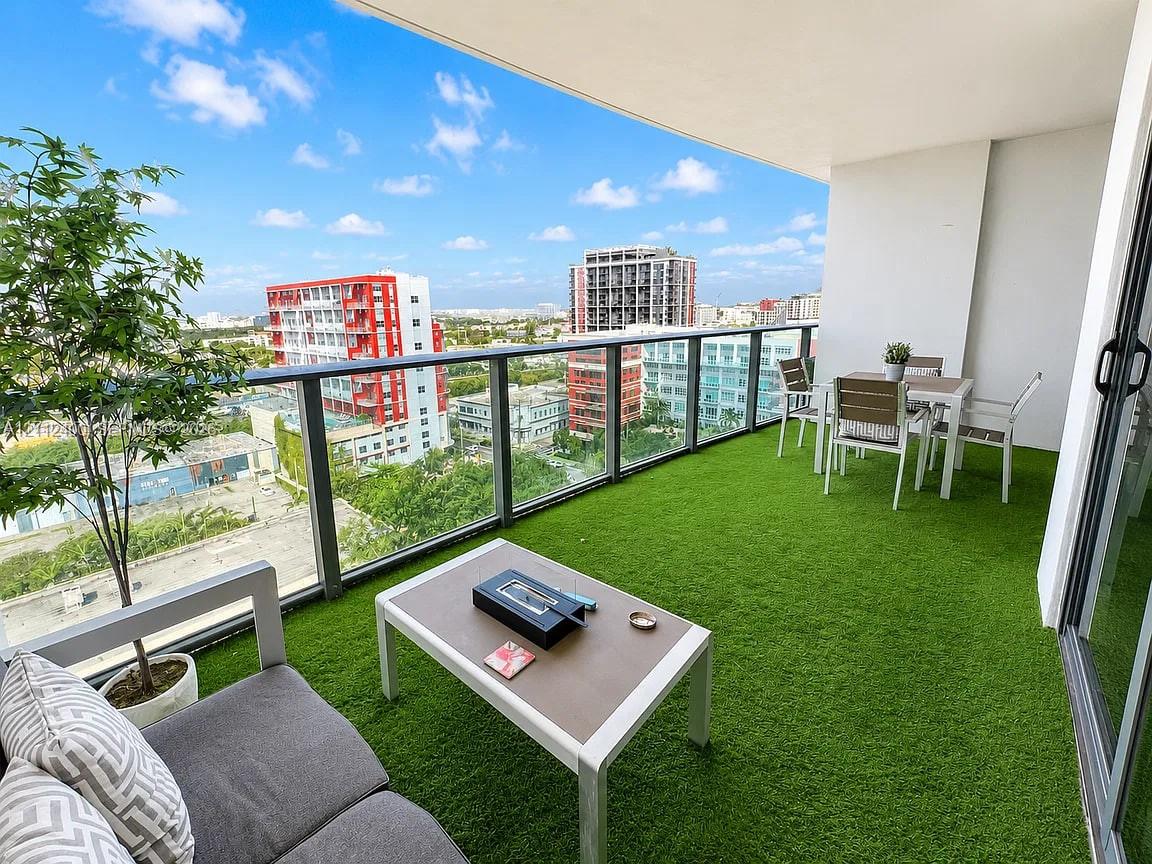 Covered balcony with synthetic turf flooring, glass panel railing, and expansive urban scenery Covered balcony with synthetic turf flooring, glass panel railing, and expansive urban scenery